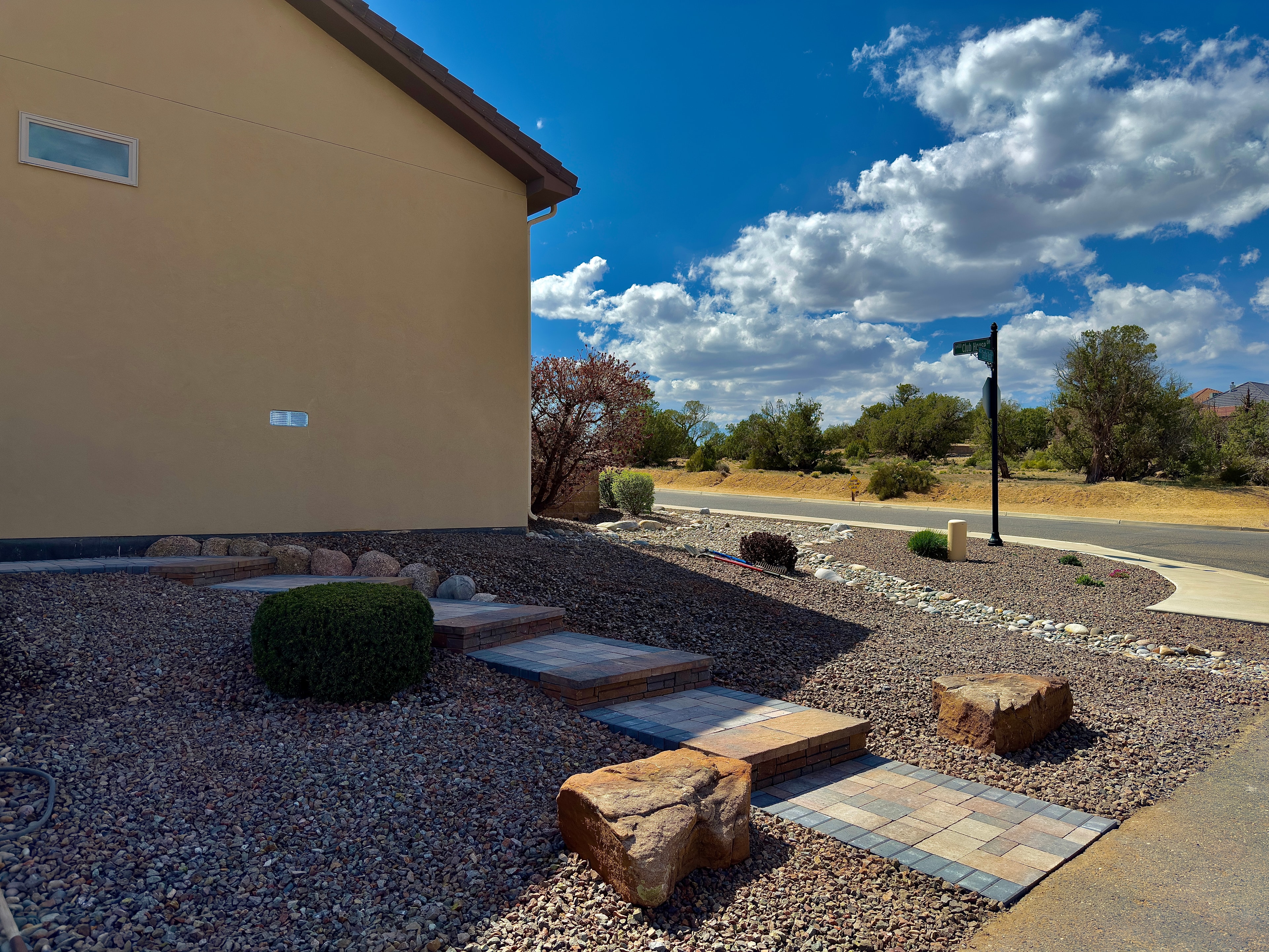 Paver staircase with moss rock accents, retaining wall, and decorative gravel installed in Farmington NM by High Desert NativeScapes