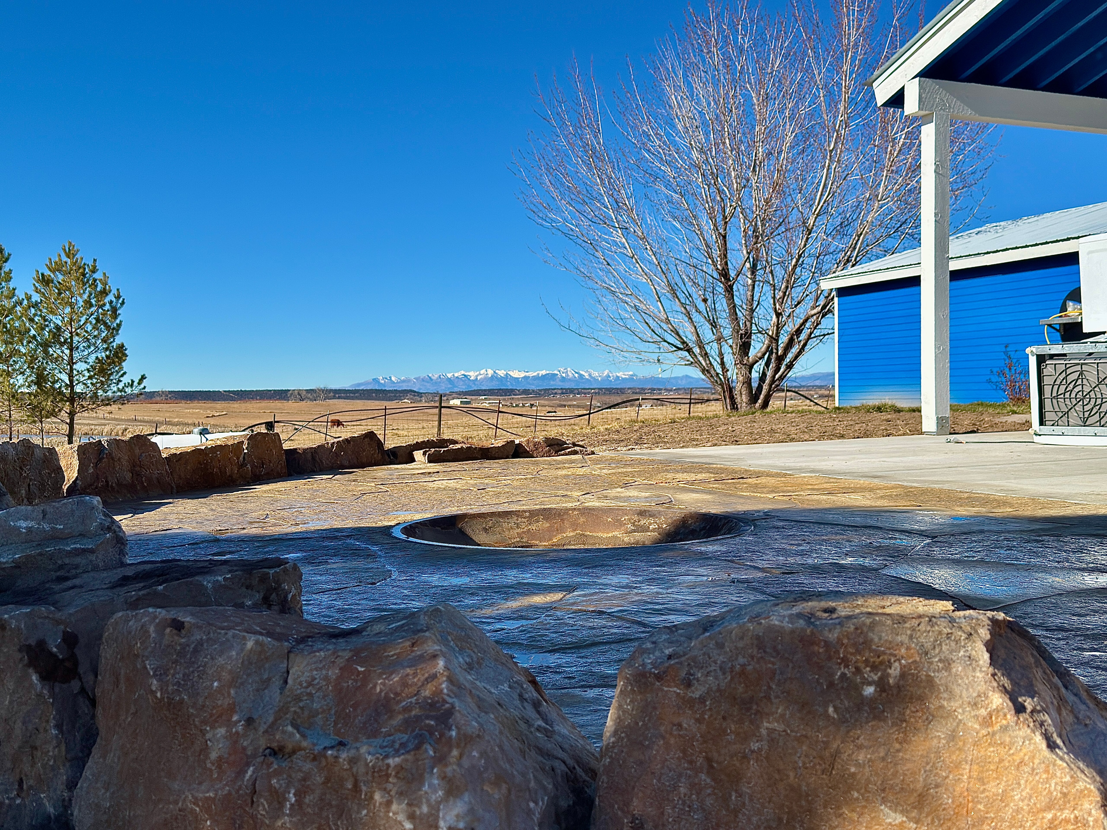 Flagstone fire pit patio with moss rock border and snow-capped La Plata Mountain views in Farmington NM — High Desert NativeScapes