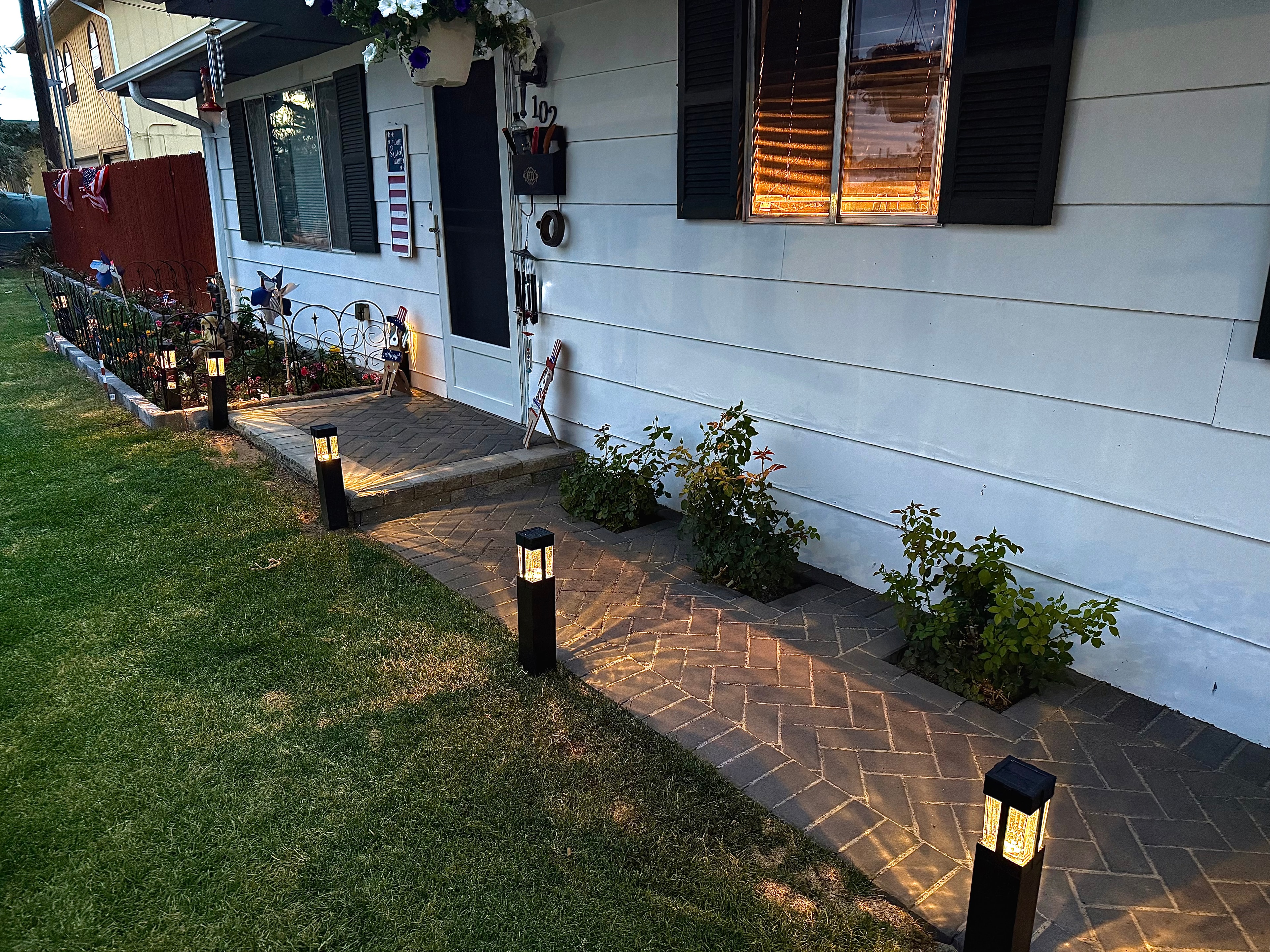Front yard herringbone paver walkway with entry step, grey-stone block garden bed borders, and bollard landscape lighting in Farmington NM — High Desert NativeScapes